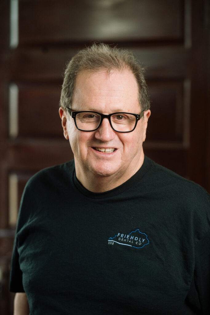 Dr. Rush, dentist at Friendly Dental Co, wearing glasses and smiling